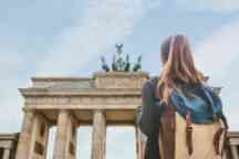 旅游有一个背包的女孩看在柏林勃兰登堡门