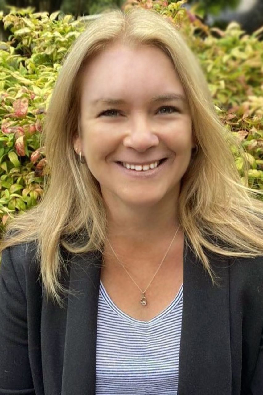 Amanda Megarrell 阿曼达有一头长长的金发,穿着一件黑色运动夹克和一件条纹衬衫。