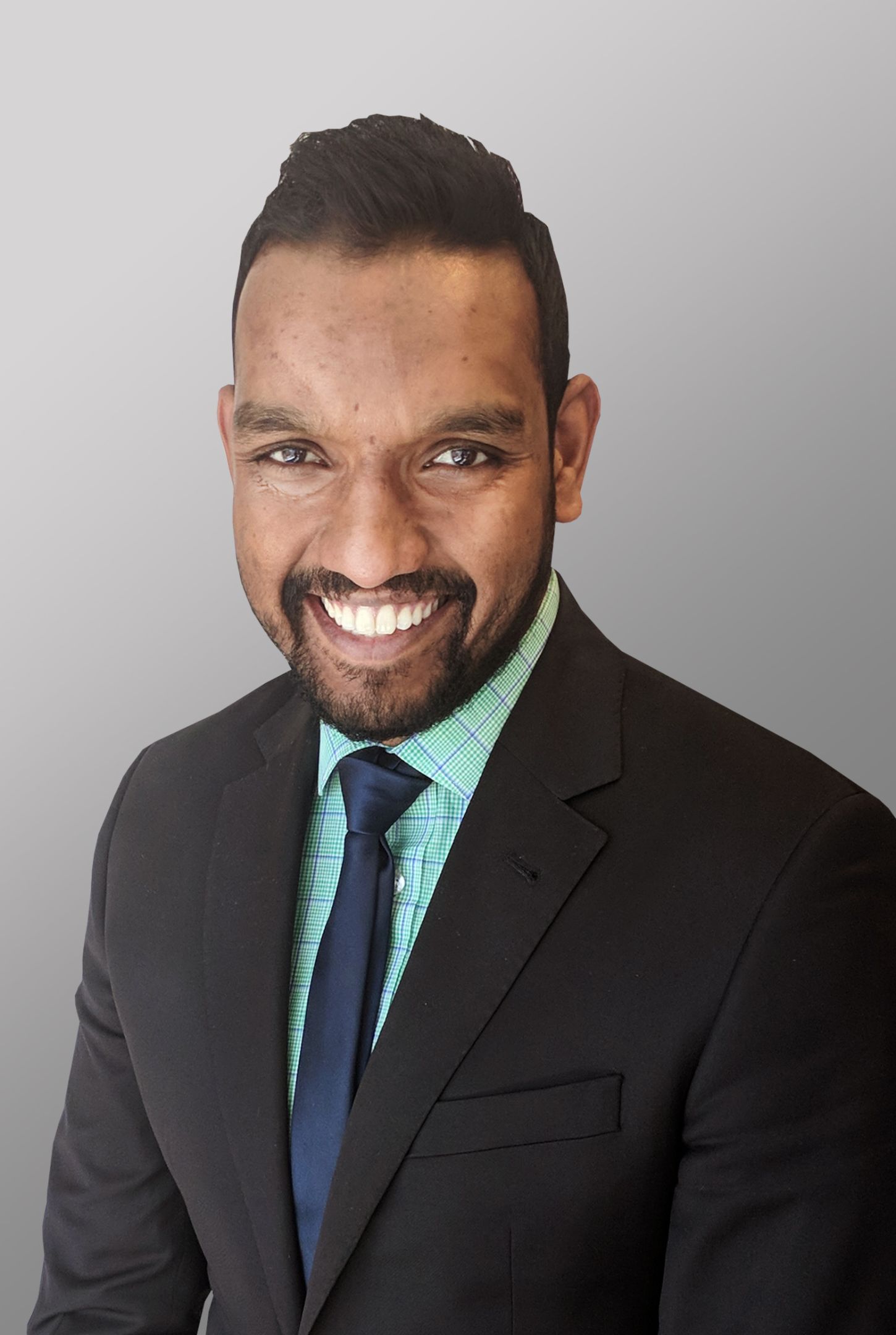 Suj Pillai 一位西装革履的职业男士面带微笑。