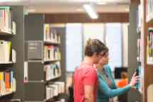 工作人员帮助学生在图书馆找书