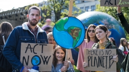 年轻人聚集在户外抗议气候行动，举着写有“行动起来!”和“没有B行星”，还有一个扩音器。