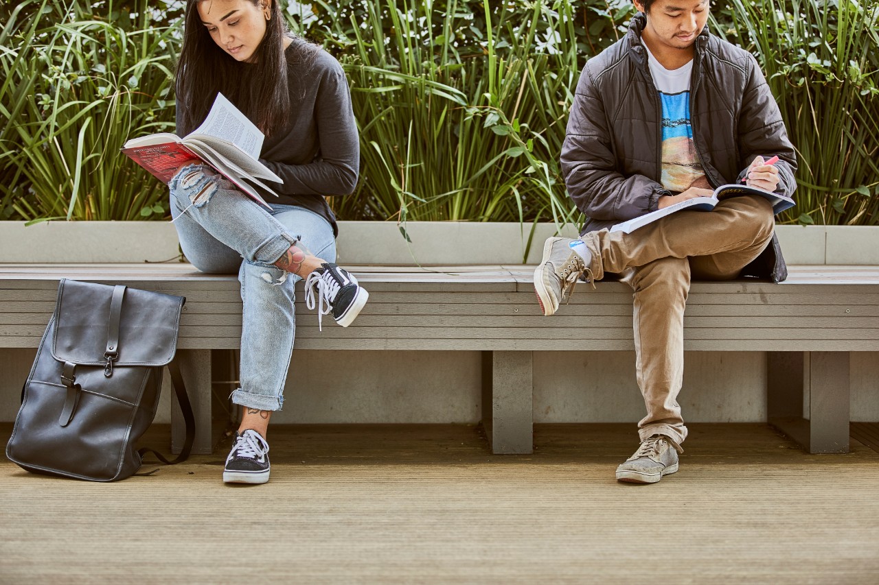 两个学生在斯威本大学霍桑校区的户外空间里阅读课程文本。