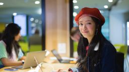 一个国际学生穿着红色贝雷帽,对着镜头微笑