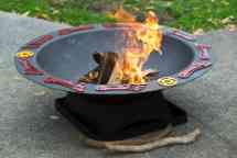 一个圆形的，黑色的火坑，装饰有红色的脚，边缘有黄色的圆圈符号，火在里面燃烧。