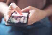 在手机应用程序中，女人的手指按着屏幕上的心形图标。网上交友应用. .