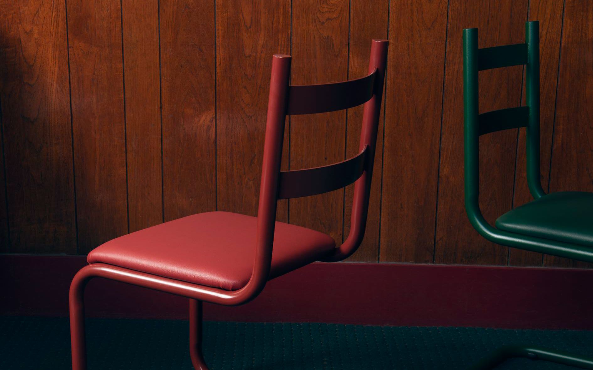 红色和绿色钢铁椅子在黑暗的木板背景下
