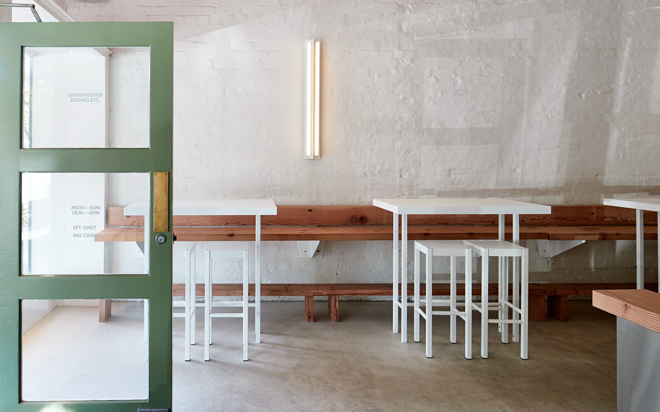 一系列白色钢铁桌子和凳子艾里,乡村空间用白色画墙壁和一扇敞开的门