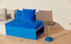 蓝色和浅灰色相间的沙发，钢质底座和织物顶部，旁边是一张小的圆边桌