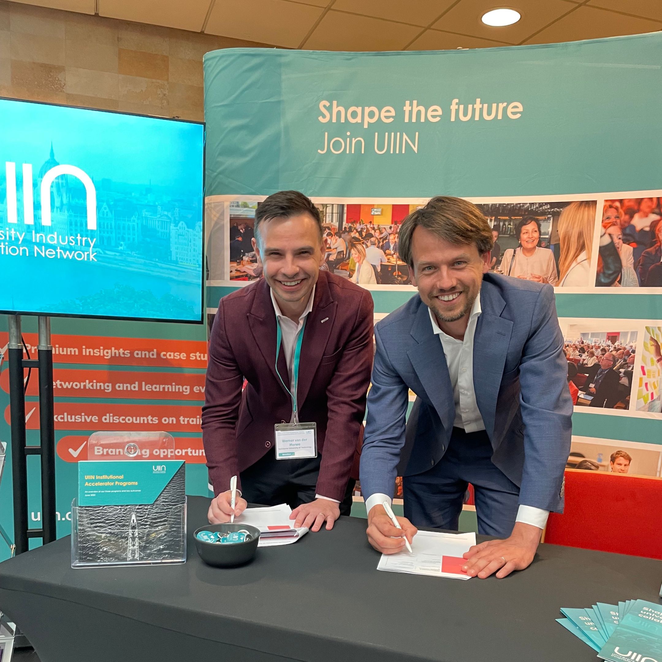 斯文本科技大学和UIIN代表微笑并签署一张纸。