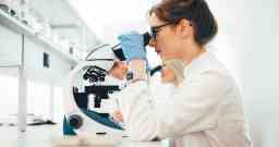 在实验室通过显微镜观察的年轻科学家