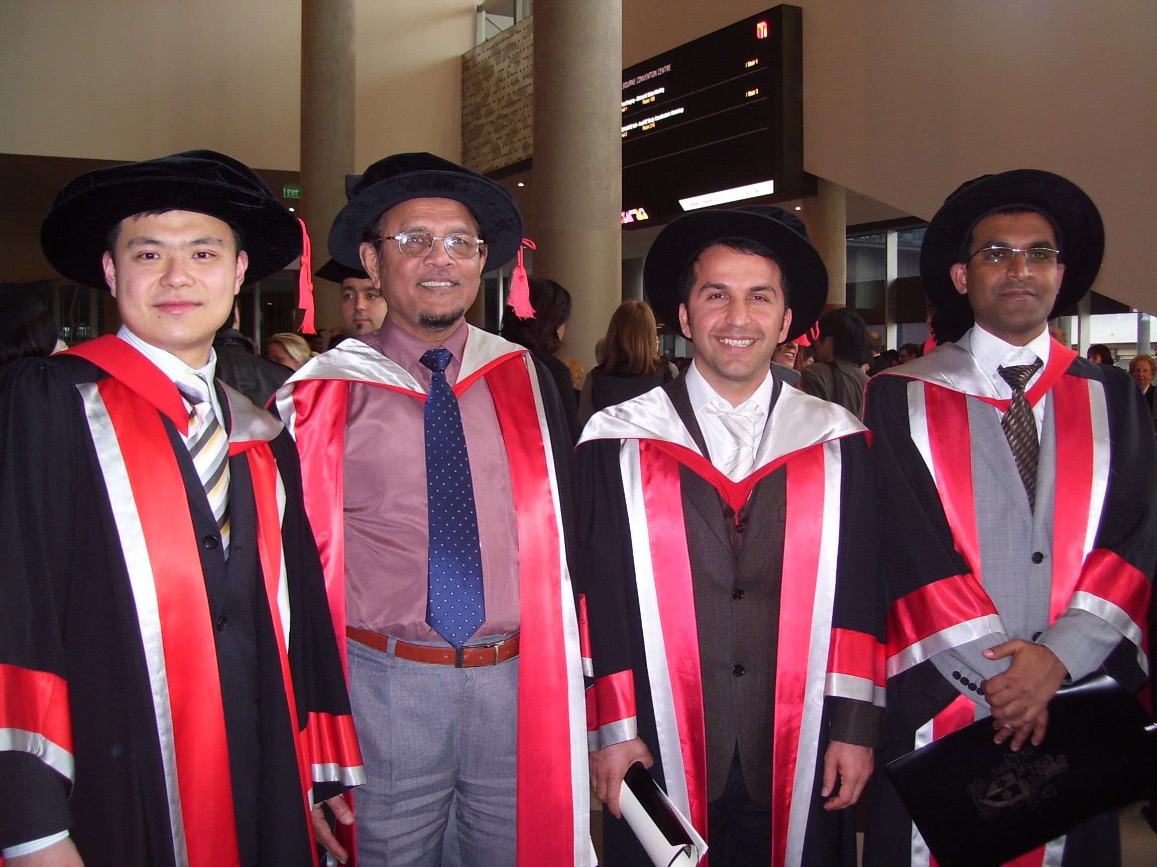 马苏德教授和他的三个站从左边第二个2021年的博士毕业生。都穿长袍斯文本科技大学的颜色,红色、白色和黑色。