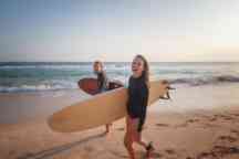 年轻夫妇快乐微笑冲浪者在海洋海岸