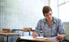 一个男学生坐在教室里复习作业。
