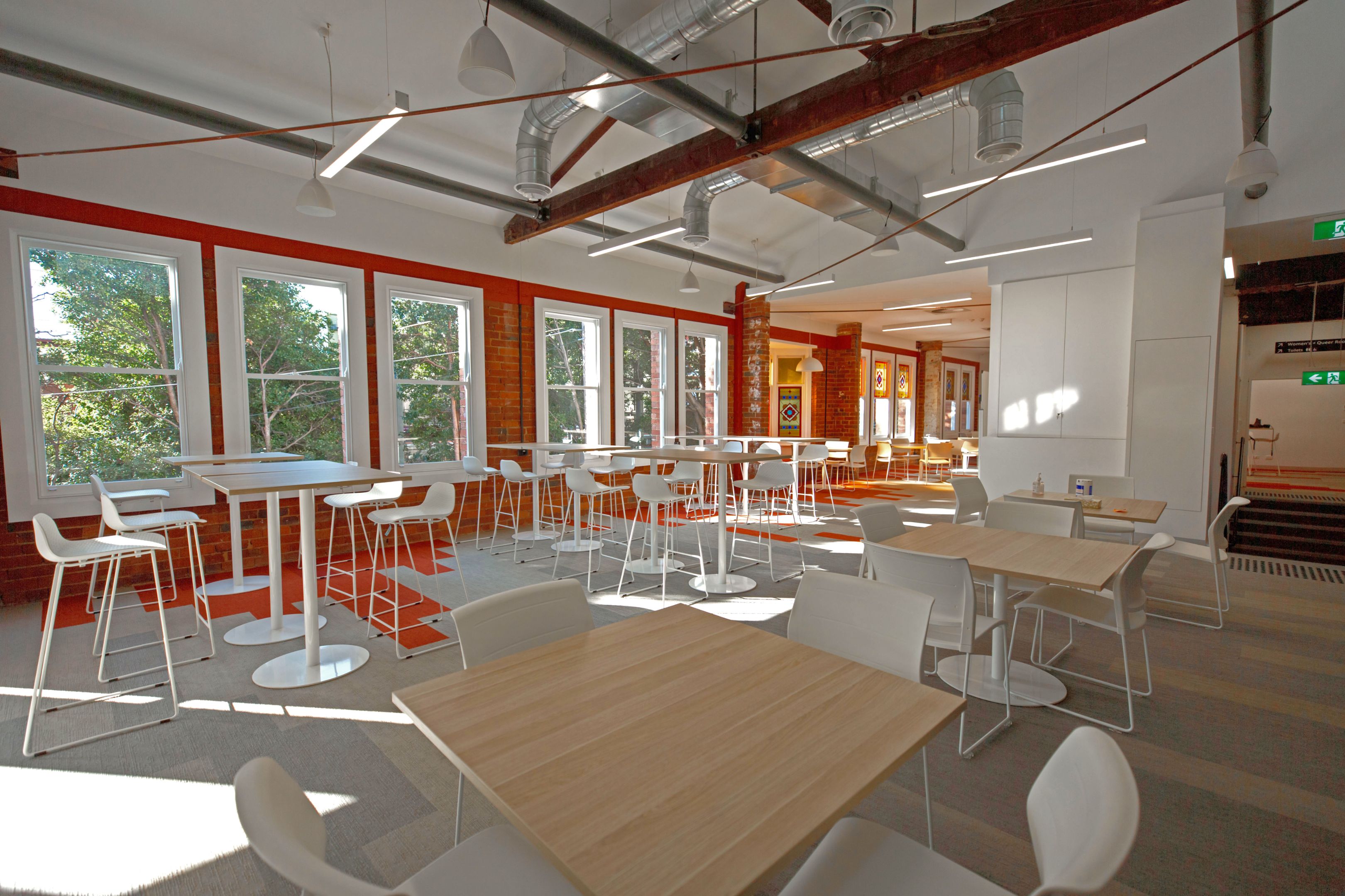 一个大的开放的学习空间，充满了自然光线，白色的椅子和轻木桌