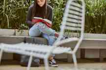 学生坐在长凳上看书，前景是椅子