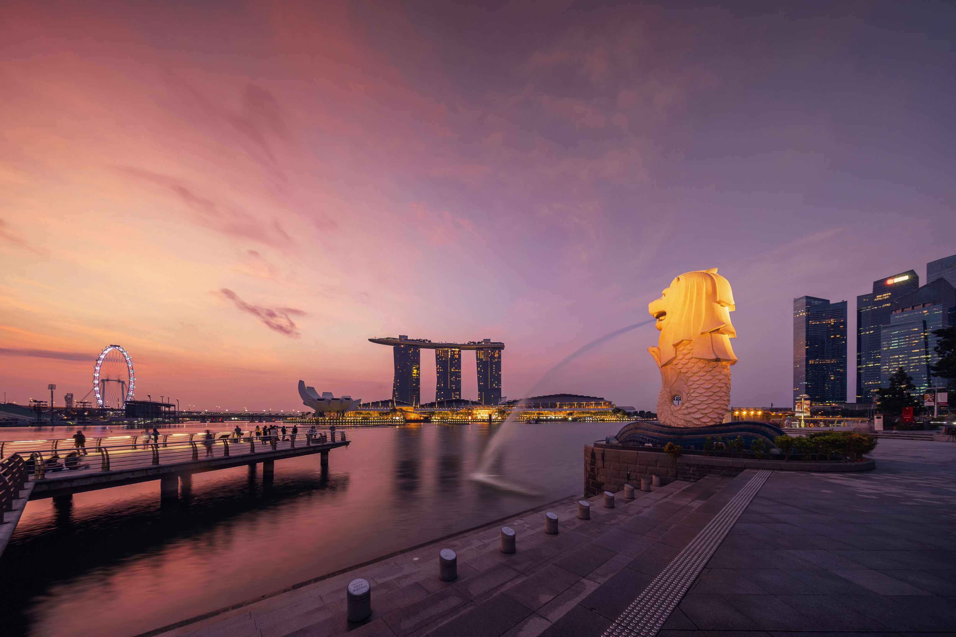 新加坡市- 2018年7月29日:鱼尾狮和滨海湾金沙日出，新加坡摩天轮和黄昏的天空。