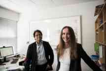 一个男人和一个女人站在办公室相邻,对着镜头微笑。