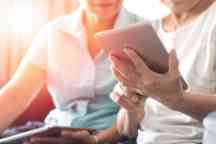 幸福老人双老年人社会生活方式与科技理念。亚洲老年妇女在幸福县家中使用平板电脑和智能手机分享社交媒体。