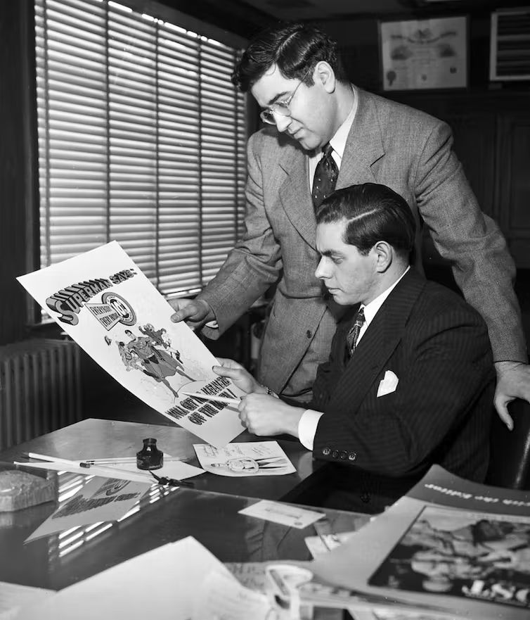 Jerry Siegel和乔•舒斯特——超人角色的创造者,都是看着海报超人漫画画的顶部和一个大标题阅读“超人”说。