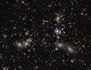 恒星旋转右边的图像中心,显示詹姆斯韦伯太空望远镜的独特衍射峰值。明亮的白色朦胧的光晕环绕来源是潘多拉的星系集群,早已规模巨大的星系群的聚集