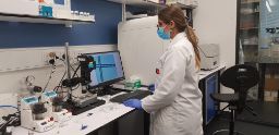 一名穿着白大褂、戴着口罩的研究人员在BioFab3D实验室的一台电脑上工作