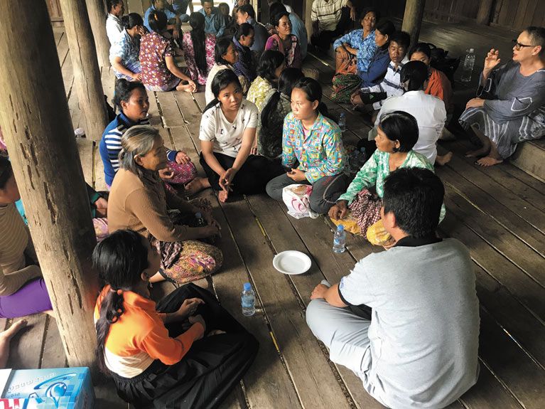 三组的人在柬埔寨坐在圆圈木地板上讨论