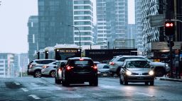 在繁忙的十字路口潮湿的道路上行驶的公共汽车和小汽车