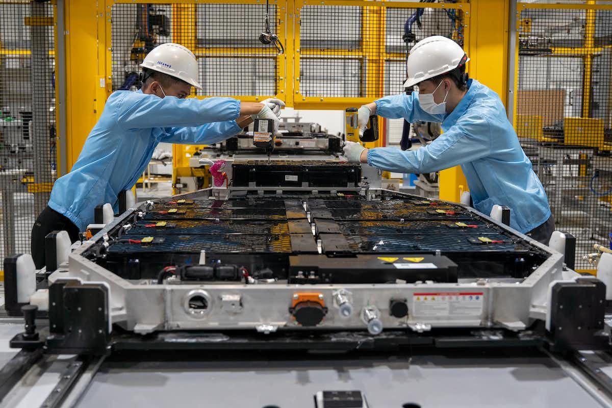两名工人在工厂调整电动汽车电池的生产线