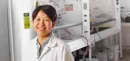 实验室大衣的女人笑着站在面前的实验室设备。