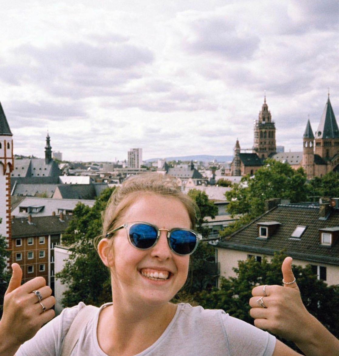 女对着镜头微笑着竖起大拇指和德国城市风貌的背景