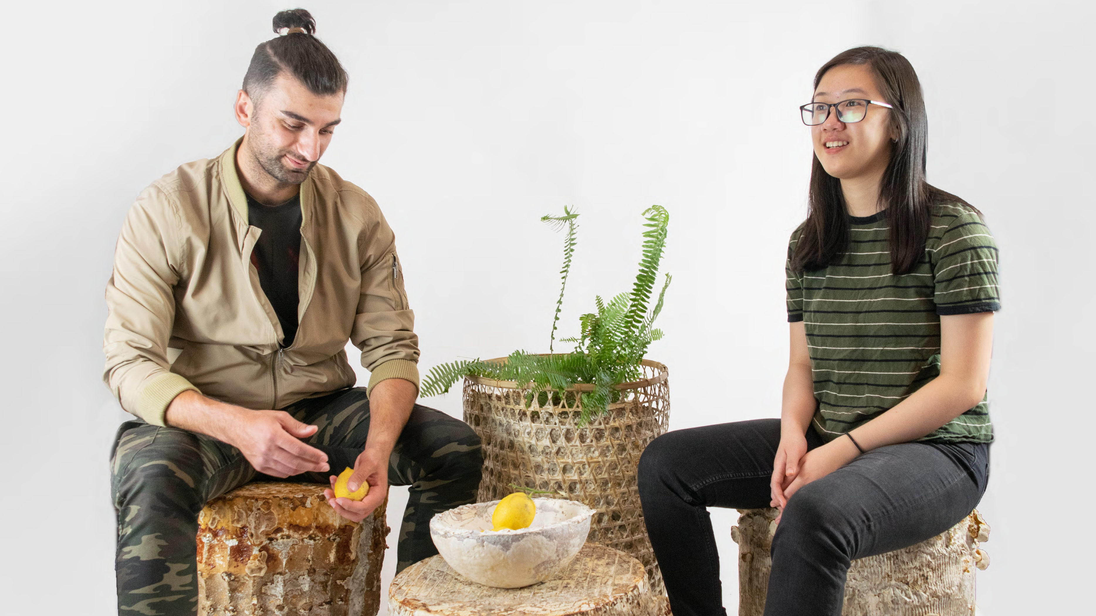 两个学生坐在他们制作的各种装饰物品的花盆上