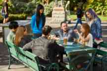 一群学生坐在一张桌子外聊天