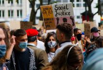 年轻人戴着面具，举着呼吁社会公正的标语，抗议种族主义