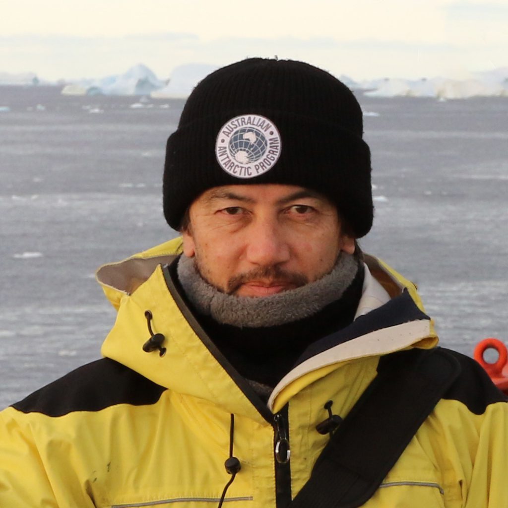 约翰穿着黄色外套和黑色无檐小便帽乘坐船在南极地区