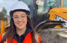 Decmil专业的照片放置学生凯尔西英戴着安全帽和安全背心在一个建筑工地。