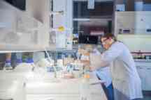 两个学生安全眼镜,身穿白色外套,在化学实验室工作
