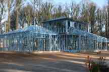 蓝色的钢框架半建造房屋的大树在后台