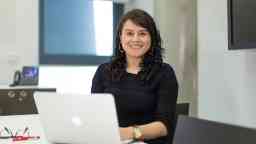 斯文本科技大学学生戴安娜坐在桌子,微笑可以用一台苹果笔记本电脑在直立位置。