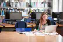 女学生在笔记本在高校图书馆工作