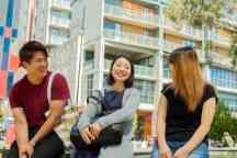 三个国际学生坐在外面山楂校园花园
